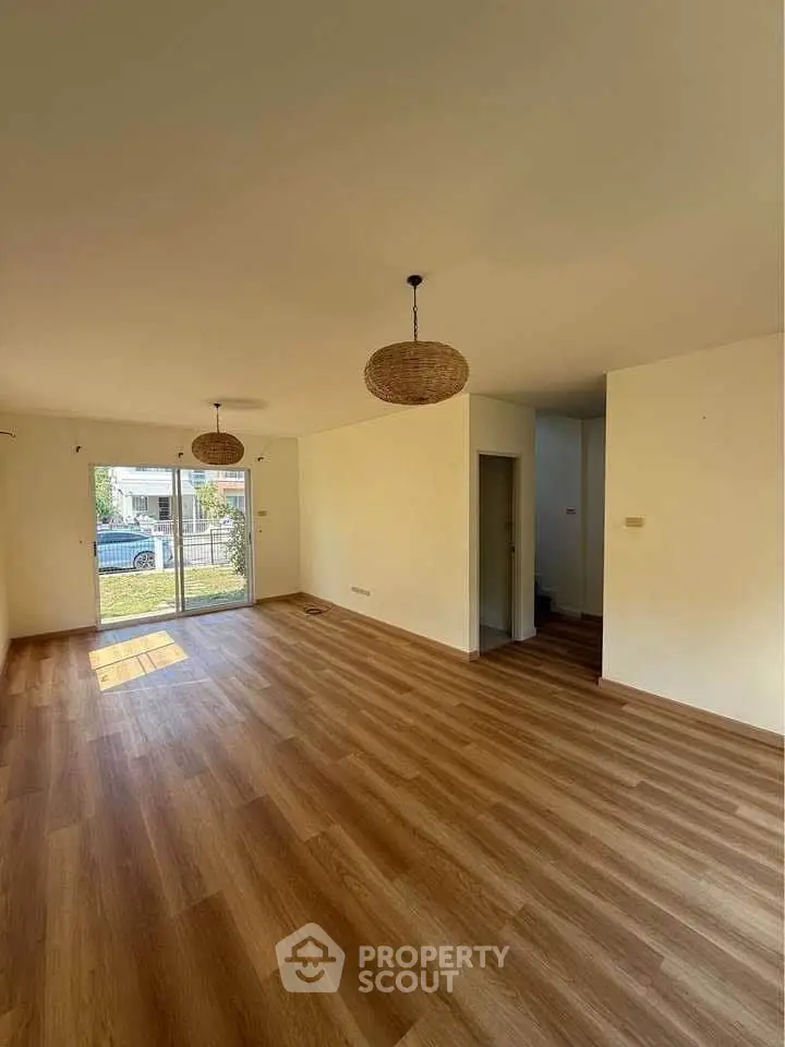Spacious living room with wooden flooring and large windows for natural light.
