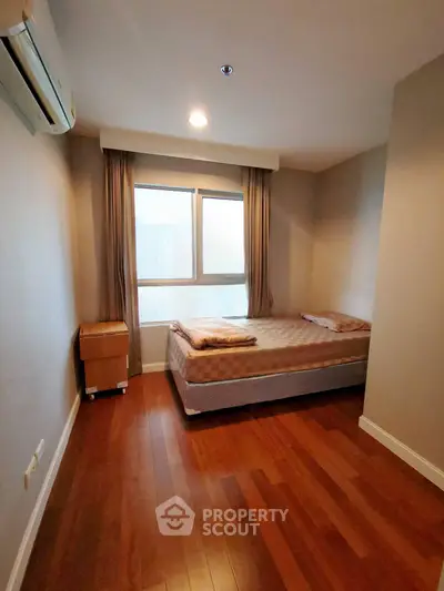 Cozy bedroom with wooden flooring and natural light from large window