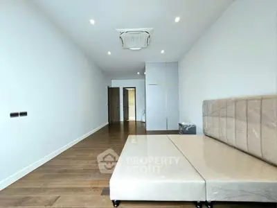 Spacious modern bedroom with wooden flooring and minimalist design