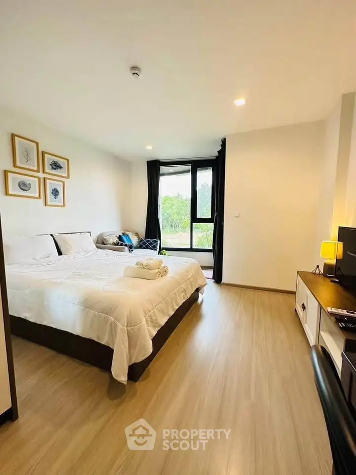 Spacious bedroom with modern decor and large window offering natural light and serene views.
