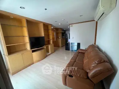 Spacious living room with leather sofa and built-in wooden shelves, perfect for modern living.