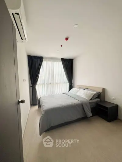 Modern bedroom with cozy bed and natural light, perfect for relaxation.