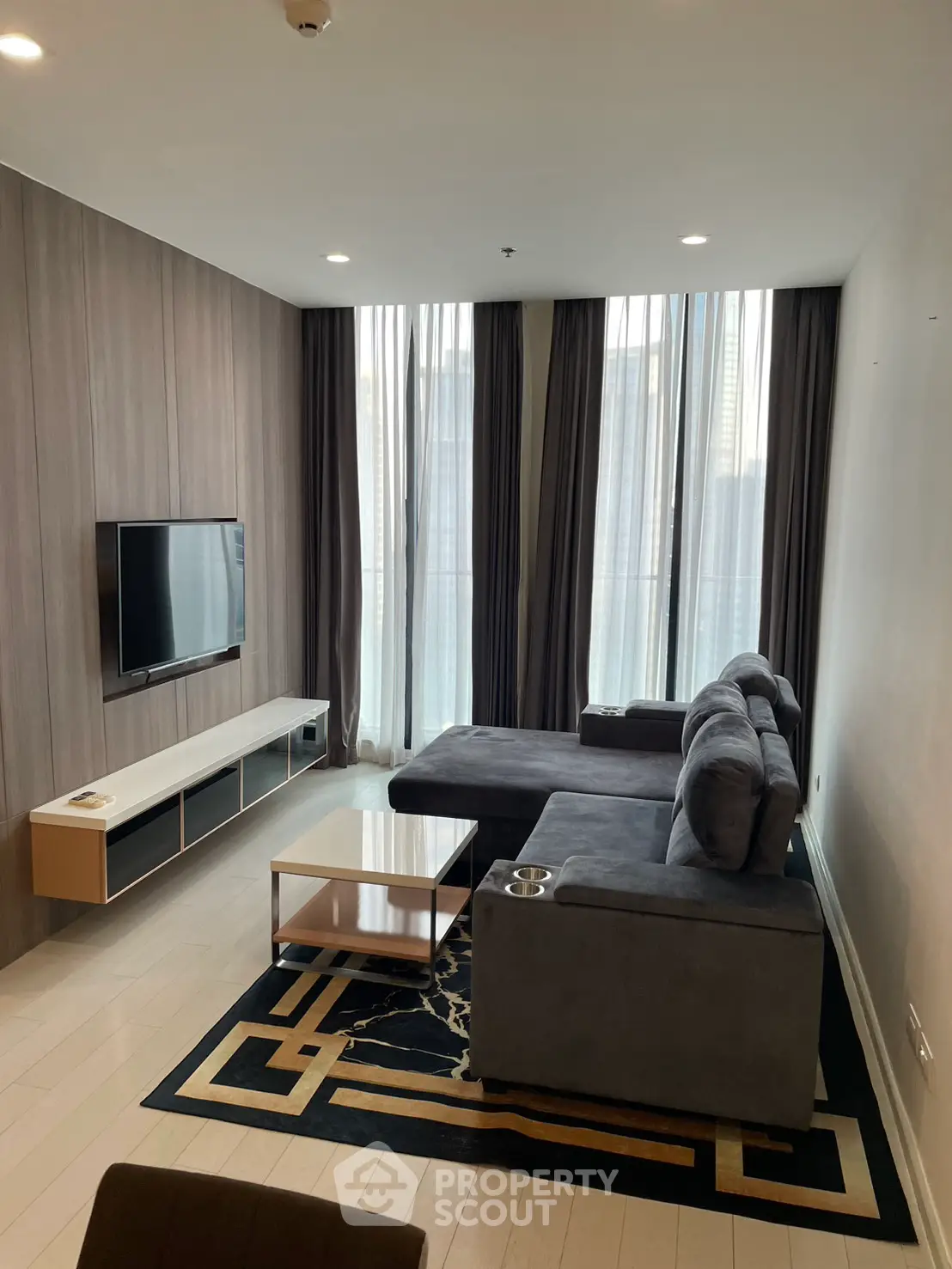 Modern living room with sleek furniture and floor-to-ceiling windows offering natural light.