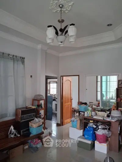Spacious living room with elegant chandelier and ample natural light, perfect for family gatherings.