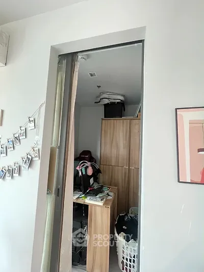 Compact storage room with wooden cabinets and laundry basket in modern apartment.