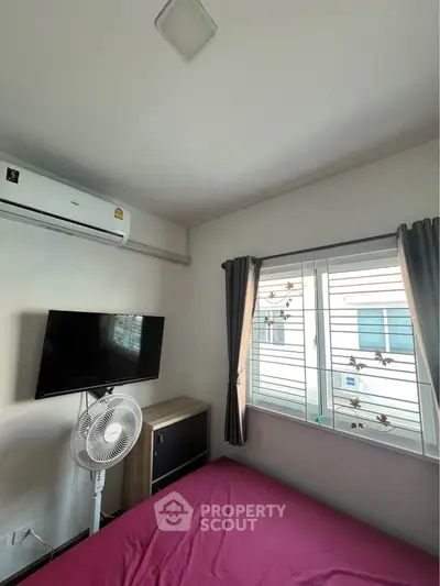 Cozy bedroom with air conditioning, wall-mounted TV, and window view.