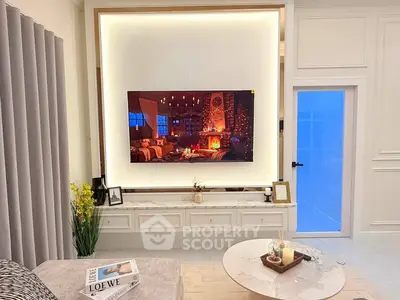 Luxurious living room with modern decor and ambient lighting, featuring a large wall-mounted TV and elegant furnishings.