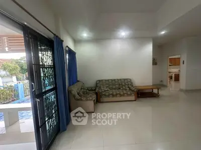 Spacious living room with cozy sofas and poolside view, perfect for relaxation.