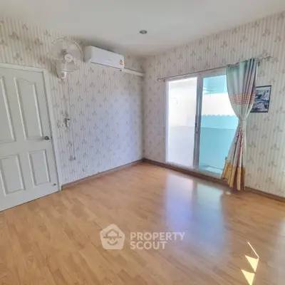 Bright empty room with wooden flooring and air conditioning, ready for customization.
