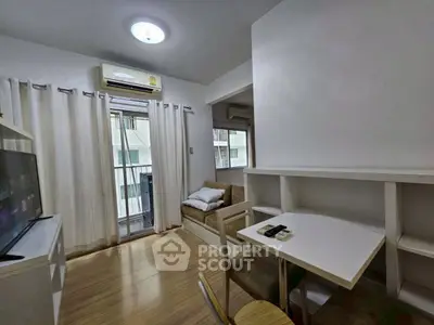 Cozy living room with natural light, modern furnishings, and a small balcony view.