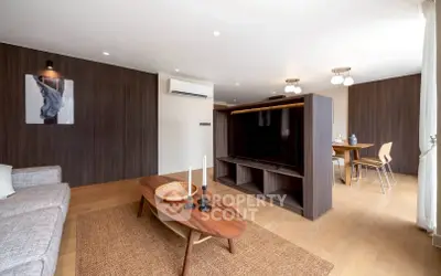 Modern living room with stylish wooden furniture and open dining area, featuring a large TV and elegant decor.