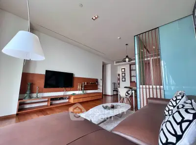 Modern living room with sleek furniture and stylish decor, featuring a large TV and elegant lighting.