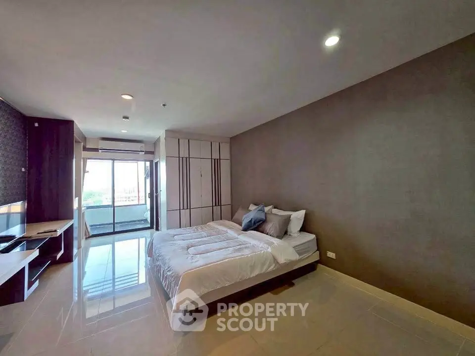 Spacious modern bedroom with large windows and sleek furnishings in a luxury apartment.