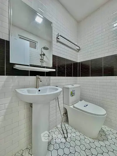 Modern bathroom with sleek white fixtures and geometric tile flooring.