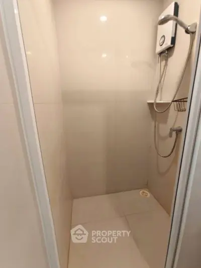 Compact shower area with modern fixtures in minimalist bathroom design.
