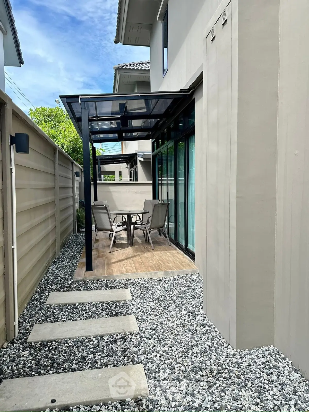Charming outdoor patio with modern glass canopy and cozy seating area.