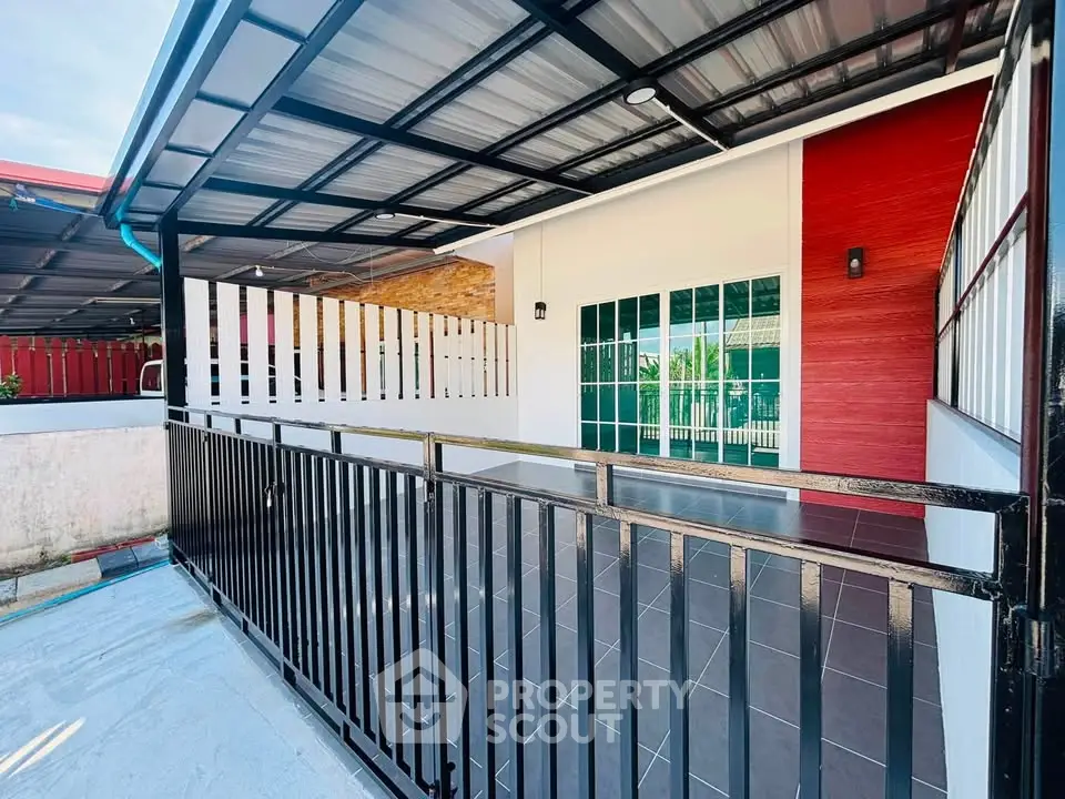 Modern home exterior with sleek metal railing and covered patio area.