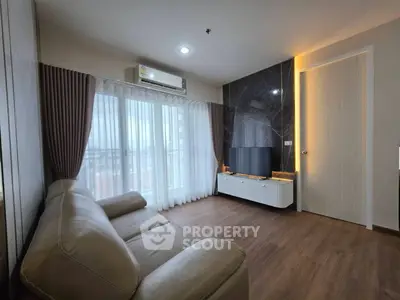 Modern living room with sleek design, featuring a leather sofa, wall-mounted TV, and large window with city view.