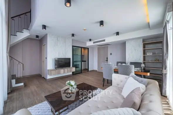 Luxurious modern living room with elegant decor and open layout, featuring a stylish staircase and dining area.