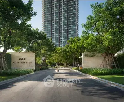 Luxurious high-rise building entrance with lush greenery and modern architecture.