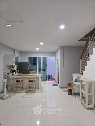Modern open-plan kitchen with sleek design and staircase, perfect for contemporary living.
