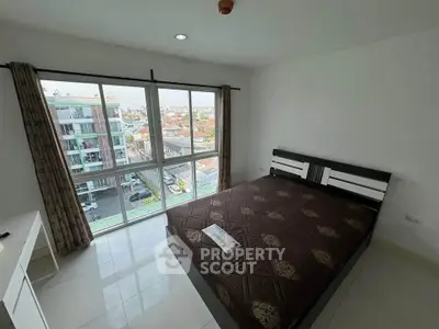 Spacious bedroom with large window offering city view in modern apartment