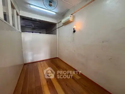 Cozy small room with wooden flooring and wall-mounted air conditioning unit.
