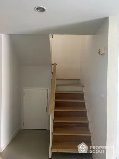 Minimalist staircase with wooden steps and white walls in modern home interior