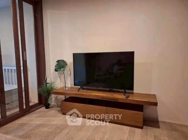 Modern living room with sleek TV setup and wooden furniture, perfect for relaxation.