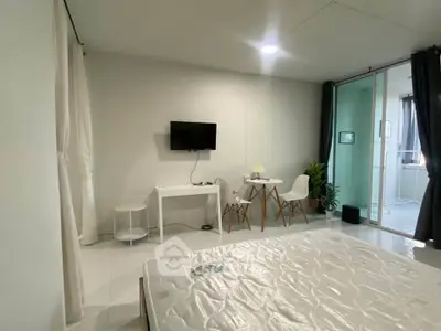 Modern bedroom with minimalist decor and wall-mounted TV in a bright apartment.