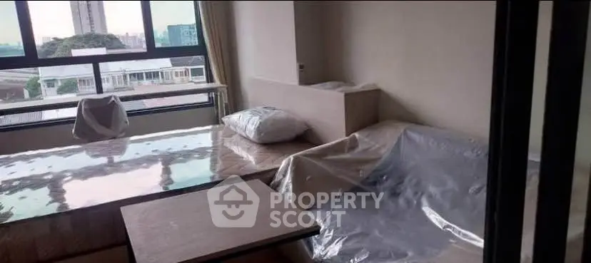 Modern living room with large windows and city view, featuring sleek furniture and natural light.