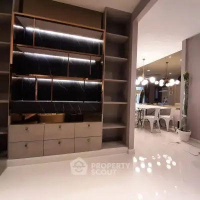 Modern interior with sleek shelving and elegant dining area, featuring contemporary lighting and polished flooring.