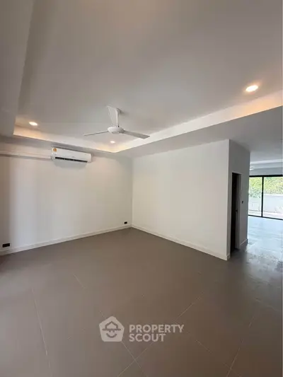 Spacious unfurnished living room with modern ceiling fan and air conditioning, ideal for customization.