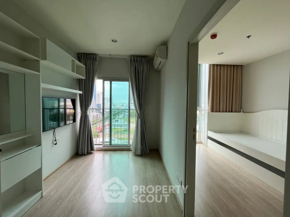 Spacious and modern living room with abundant natural light, sleek built-in shelves, and a cozy nook, leading to a balcony with city views.