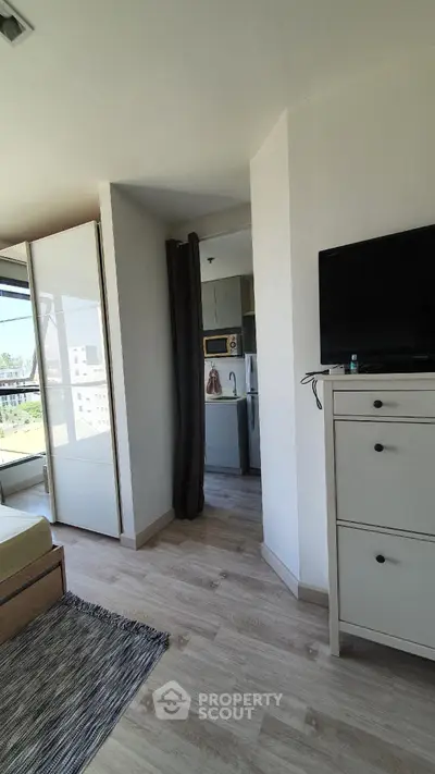 Modern apartment interior with sleek design and natural light, featuring a cozy living area and partial kitchen view.
