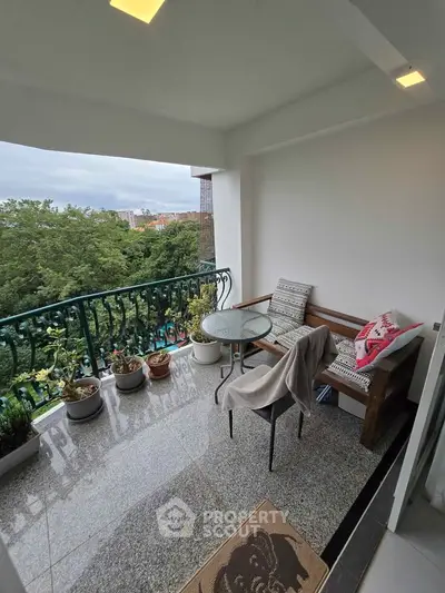 Charming balcony with seating and lush green view, perfect for relaxation.
