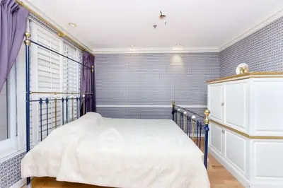 Elegant bedroom with classic decor and ample natural light.