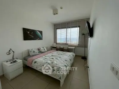 Cozy bedroom with modern decor and large window offering natural light.