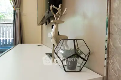 Modern interior decor with geometric terrarium and stylish deer sculpture on sleek white surface.
