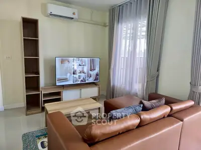 Modern living room with leather sofa and flat-screen TV, featuring elegant curtains and stylish decor.