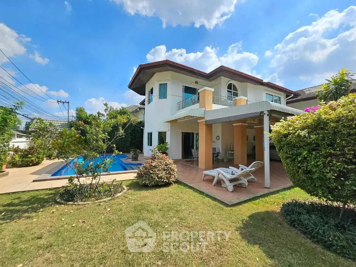 Stunning two-story house with pool and lush garden under a bright blue sky.