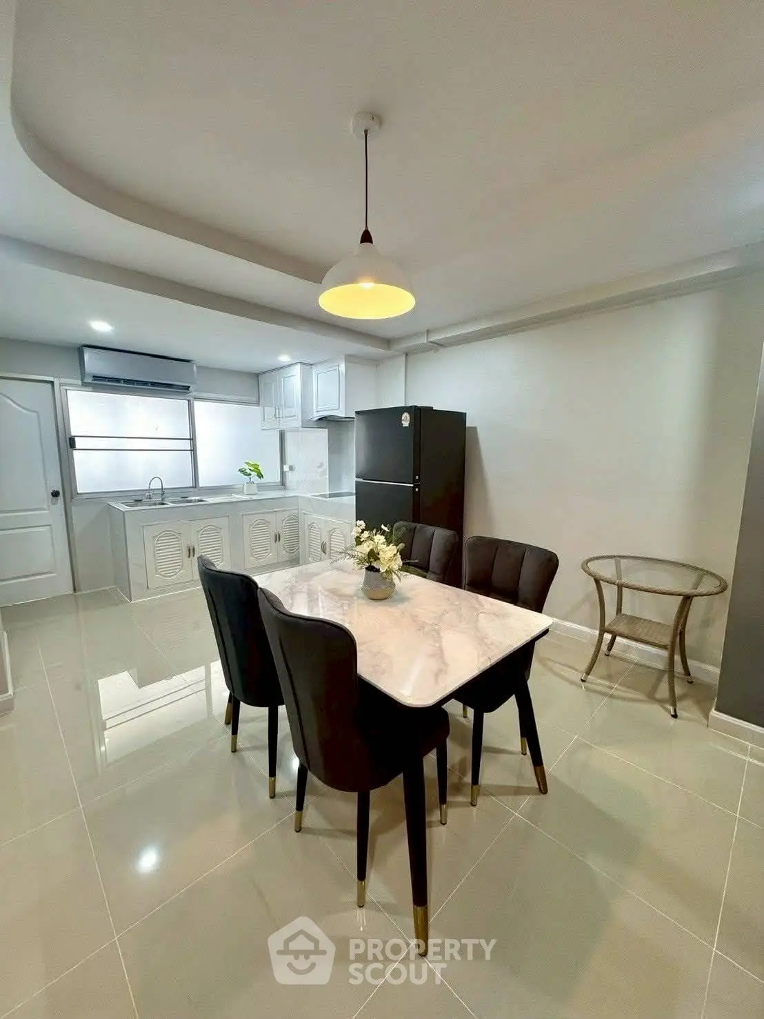 Modern kitchen with dining area featuring sleek black chairs and marble table, bright and spacious layout.