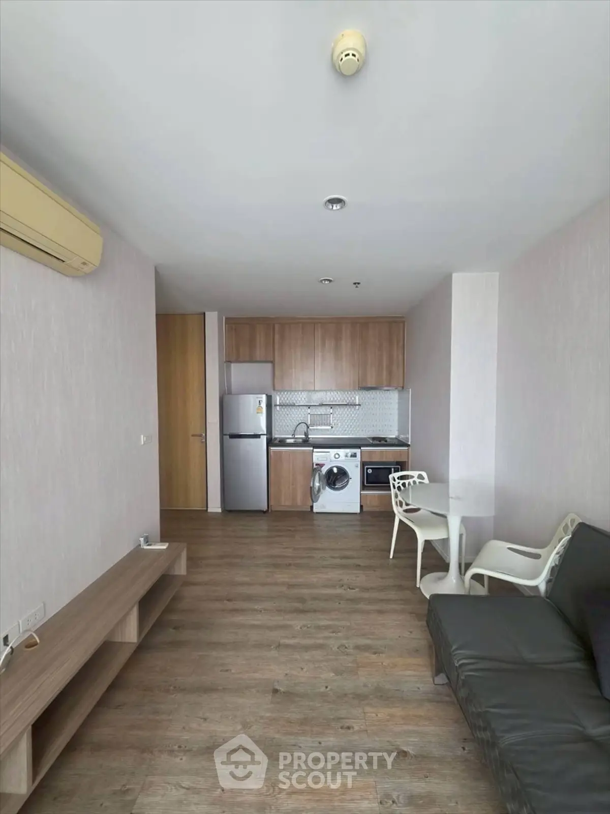 Modern apartment interior with open kitchen and living area, featuring wooden flooring and contemporary furniture.