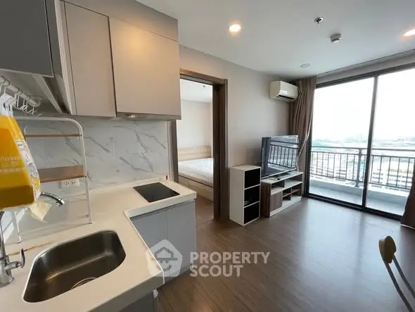 Modern apartment interior with open kitchen and living area, featuring large windows and balcony access.