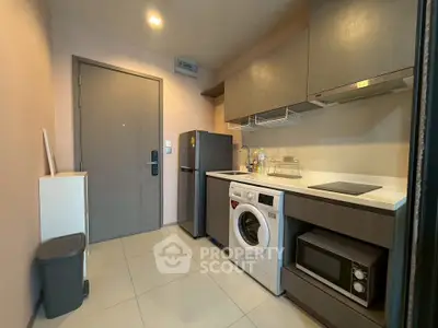 Modern compact kitchen with washing machine and microwave in sleek apartment.