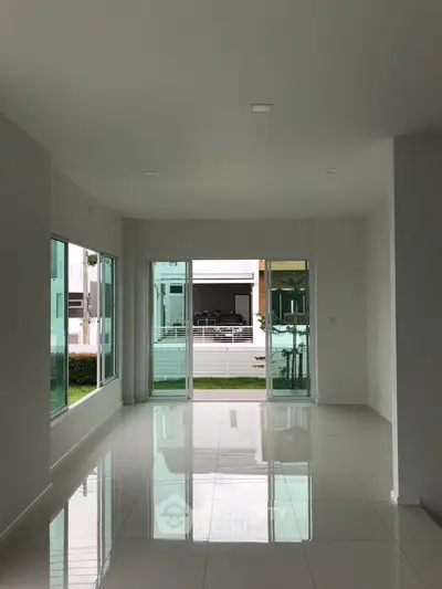 Spacious modern living room with large windows and glossy tiled floors, offering a bright and airy ambiance.