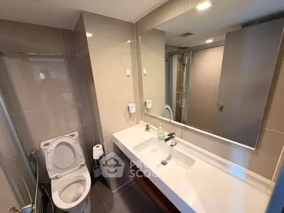 Modern bathroom with sleek fixtures and large mirror in contemporary apartment.