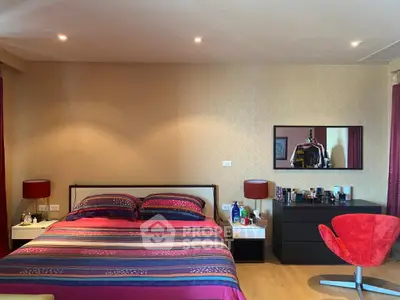 Spacious bedroom with modern decor and vibrant colors, featuring a comfortable bed and stylish furniture.