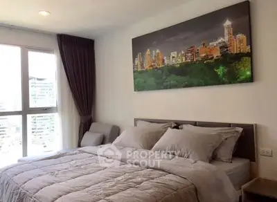 Modern bedroom with cityscape artwork and large window offering natural light.