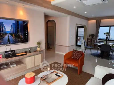 Modern living room with stylish decor and open layout, featuring a large TV and elegant dining area.